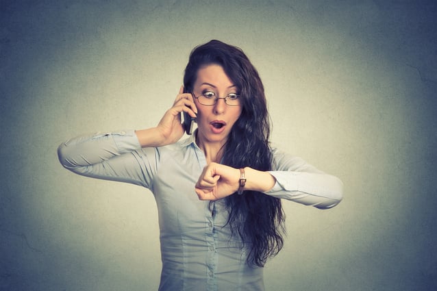 Business and time management concept. Stressed businesswoman looking at wrist watch, running late for meeting